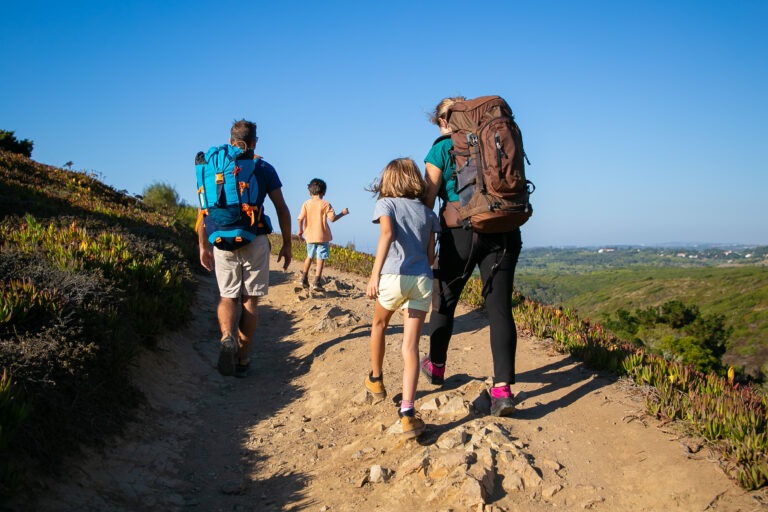 Family of travelers with backpacks walking on track